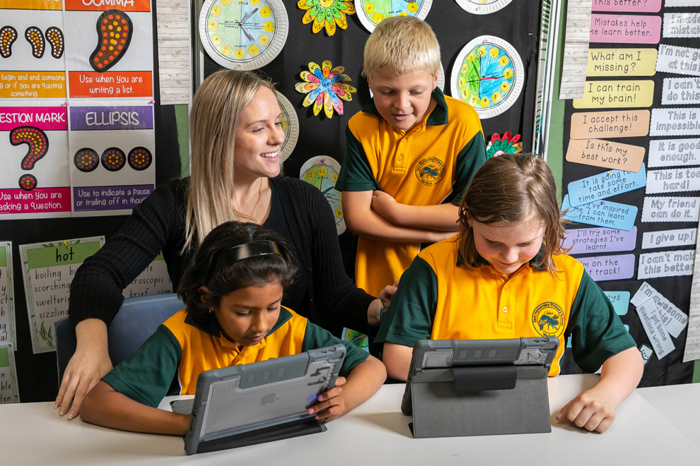 A group of three students and their teachers working on tablets.
